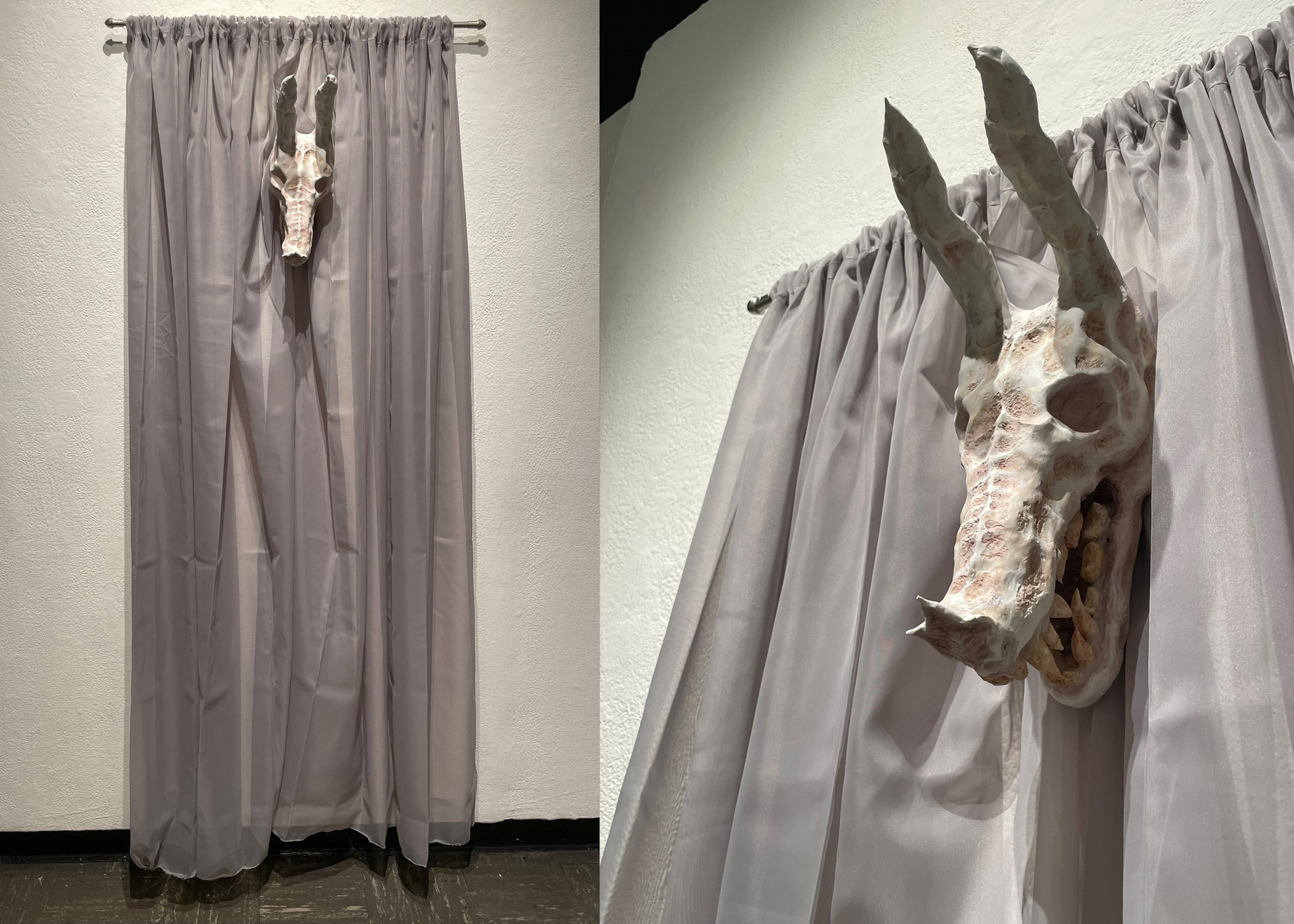 A sculpture of a beast's skull flanked by curtains.